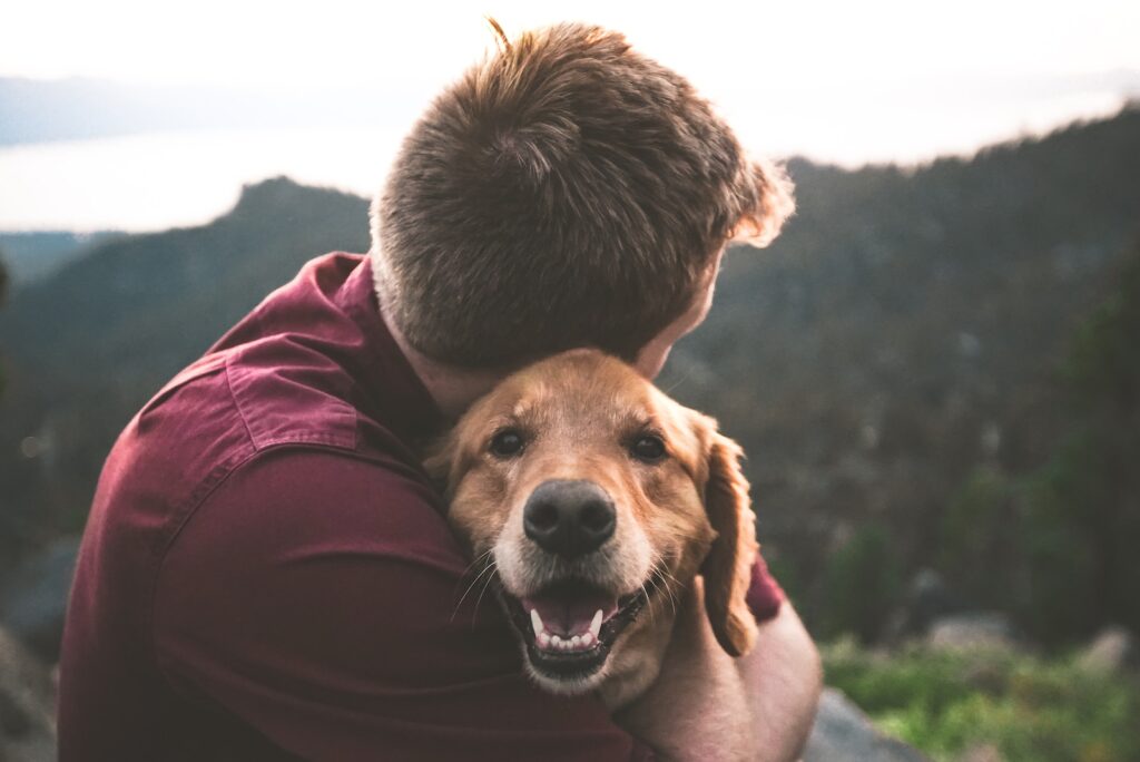 zdjęcie mężczyzny przytulającego brązowego psa